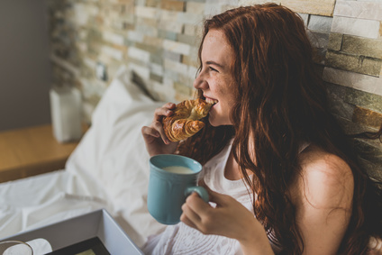 Junge Frau genießt ein Frühstück im Bett