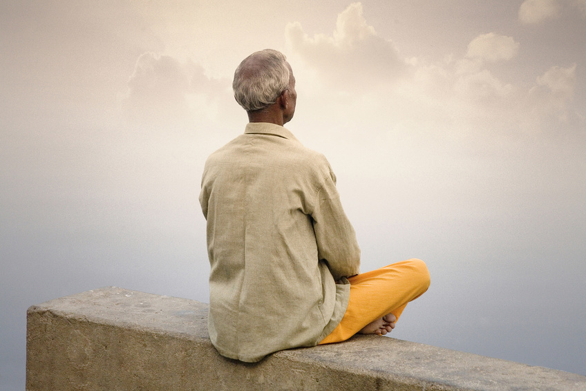 meditierender Mann auf einer Mauer sitzend